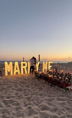 Two lovers whit a marry me sign in a beach